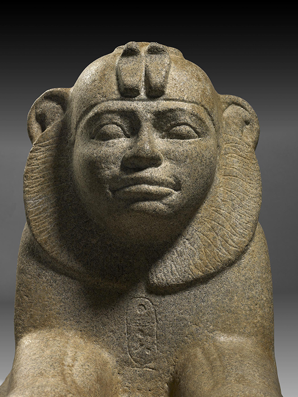 Granite (probably granite gneiss) sphinx of Taharqo wearing skull-cap and double-uraeus; cartouche on breast.