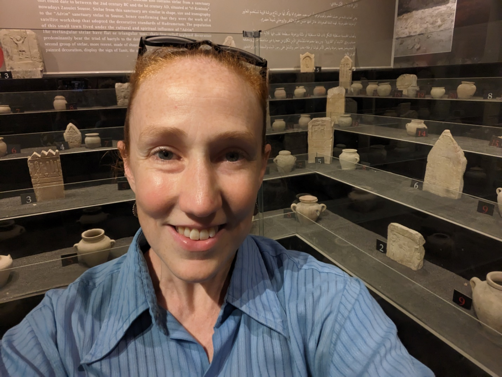 The author at the Sousse Archaeological Museum, featuring votive stelae and ceramic urns from the “Baal Hammon sanctuary” at Sousse (photo by H. Dixon).