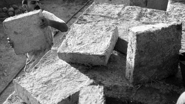 Baran Kerim Ecer lifting and stacking mud bricks