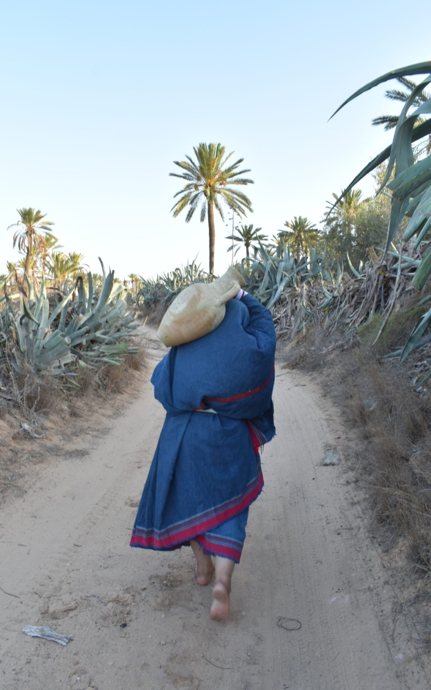 A WOMAN CARRYING A WATER JAR | إمرأة جربية تحمل جرة الماء